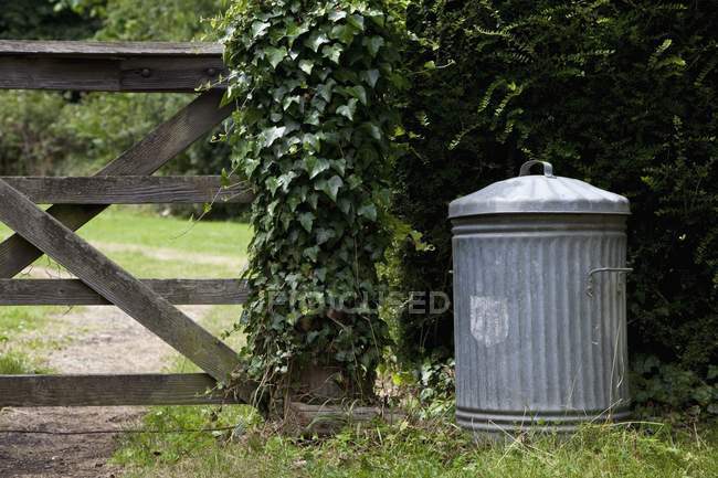 Старый металлический мусорный бак в саду — стоковое фото