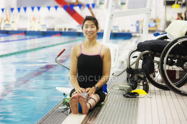 Paraplegic woman sitting at edge of swimming pool on lift — Stock Photo