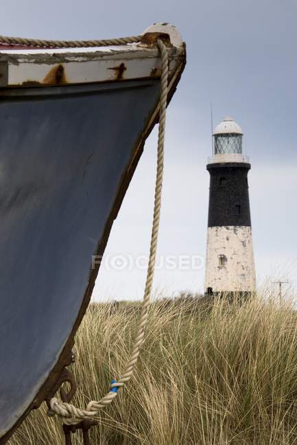 Barca abbandonata e faro — Foto stock