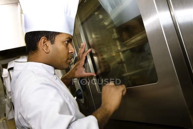 Side View Of  Chef Looking Into The Oven At Kitchen — Stock Photo