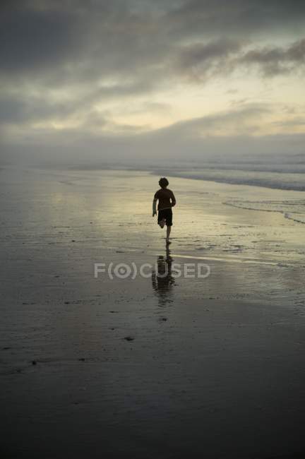 Человек бегущий по пляжу — стоковое фото