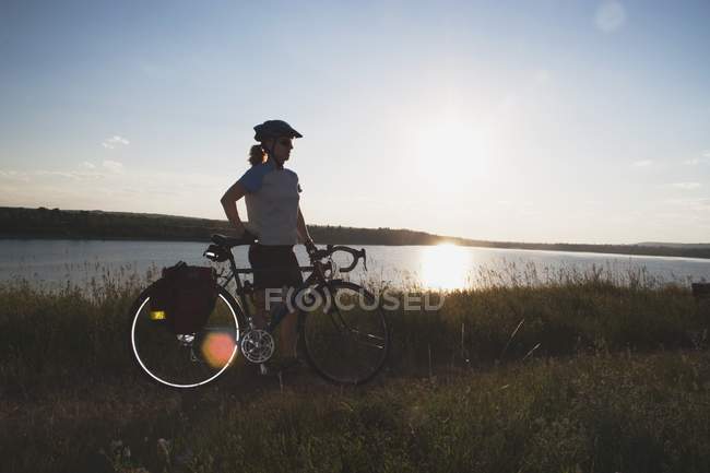 Donna con bici lungo un lago — Foto stock