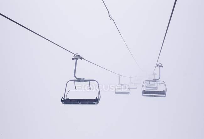 Cadeiras de elevador de esqui no nevoeiro, vista à distância — Fotografia de Stock