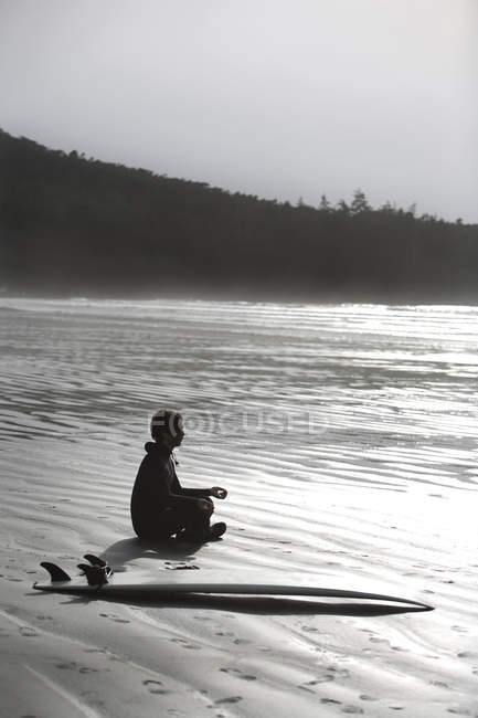 Surfista meditando en la playa - foto de stock