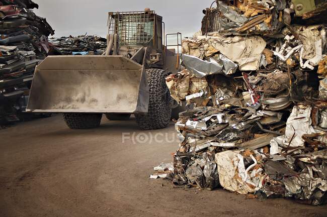Трактор, проезжающий через стопки компактного мусора — стоковое фото