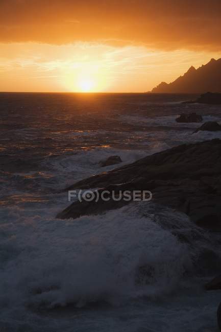 Puesta de sol a lo largo de la costa rocosa - foto de stock