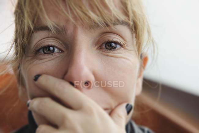 Retrato de una mujer con la mano en la boca - foto de stock