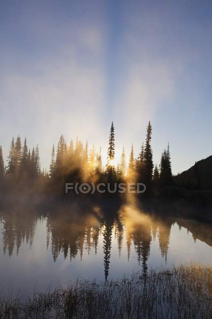 Salida del sol reflejada en el lago - foto de stock