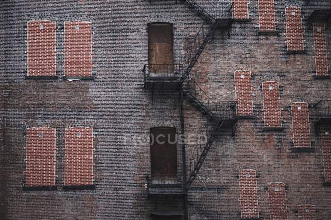 A Fire Escape Going Up The Side of a Brick Building — стоковое фото