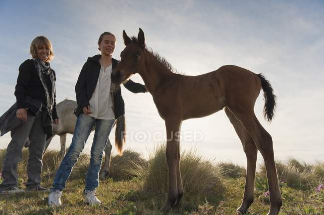 Teen girl with mother petting foal in Tarifa, Cadiz, Andalusia, Spain — Stock Photo