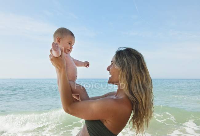 Madre jugando con la niña en la playa - foto de stock