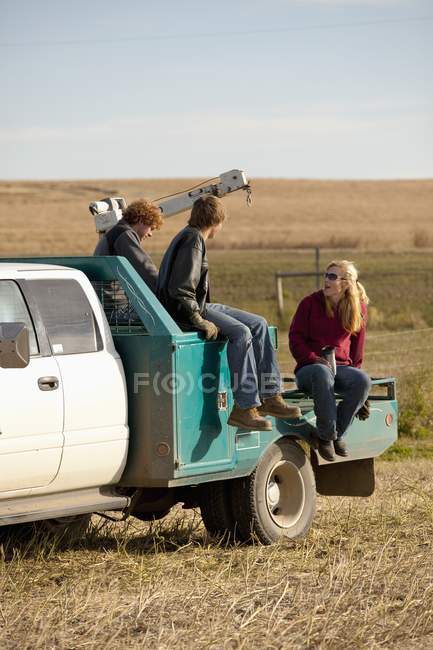 Junge erwachsene, die auf der rückseite des lastwagens in alberta, kanada sitzen und reden — Stockfoto