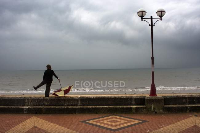Людина з парасолькою стоячи Boardwalk, Йоркшир, Англія — стокове фото