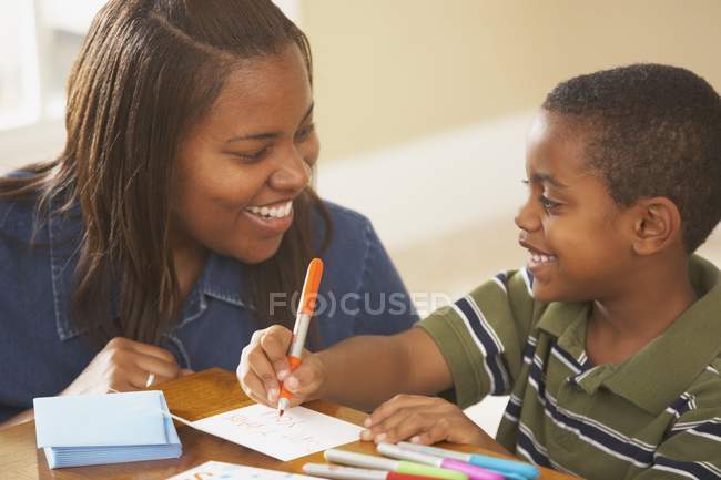 Счастливый мальчик пишет карточки с мамой — стоковое фото