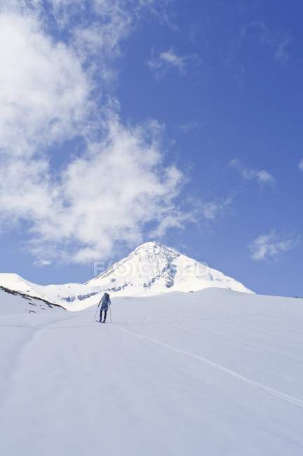 Лыжник поднимается на гору — стоковое фото