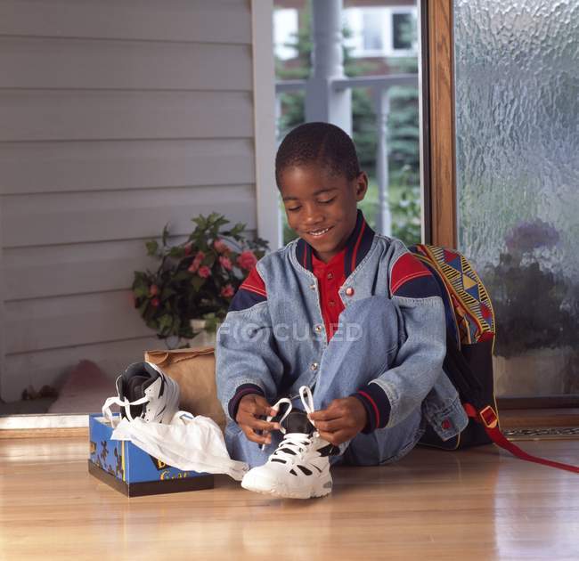 Afro-américain garçon attacher de nouvelles chaussures — Photo de stock