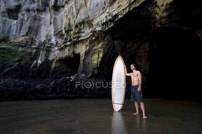 Surfista dentro una grotta a Muriwai, Nuova Zelanda — Foto stock