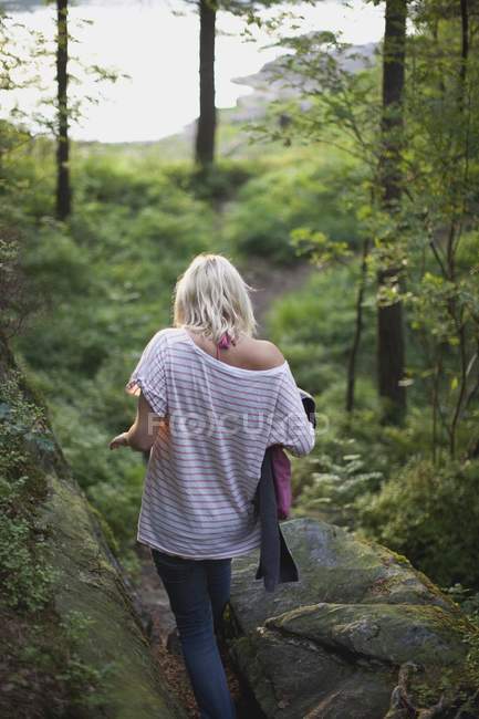 Junge Frau spaziert durch Wald zum See in Kristiansand, Norwegen — Stockfoto