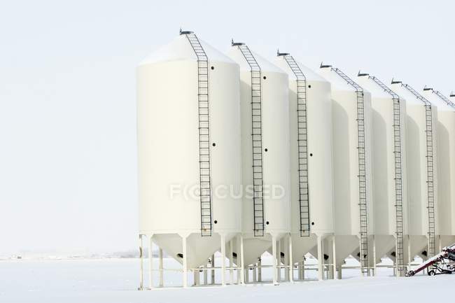 Metal grain bins in snowy field. Alberta, Canada — Stock Photo