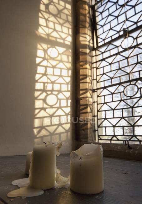 Geschmolzene Kerzen auf einem Tisch am Fenster — Stockfoto