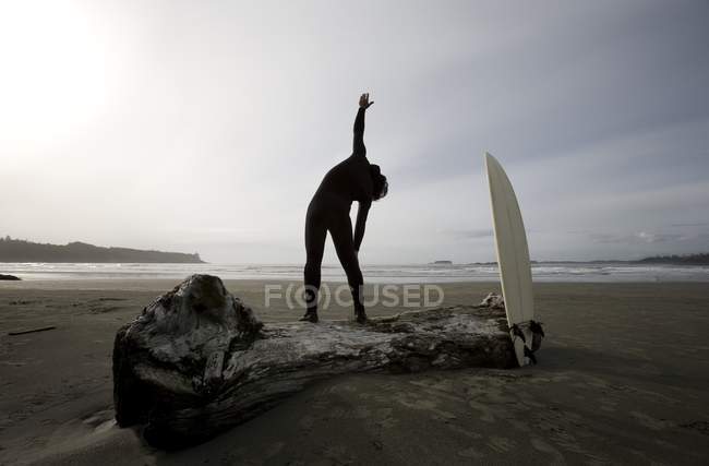 Surfista estirándose en la playa - foto de stock