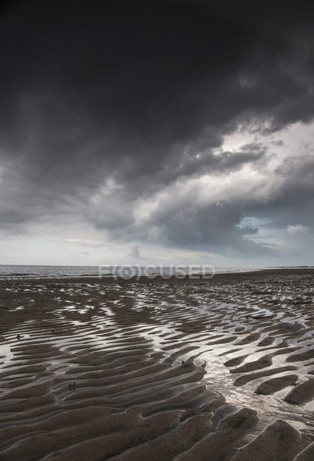 Areia ondulada sob nuvens escuras — Fotografia de Stock