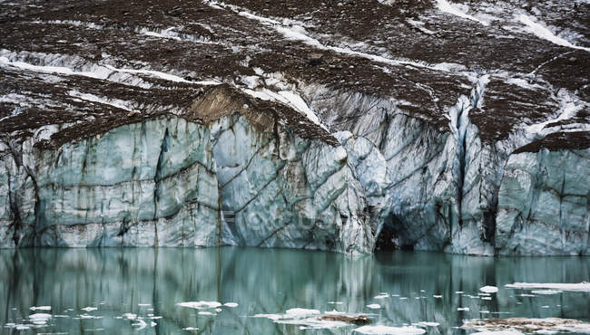 Gravelly glacier cliff reflected in small glacial lake, jasper national park, alberta, canada — Stock Photo