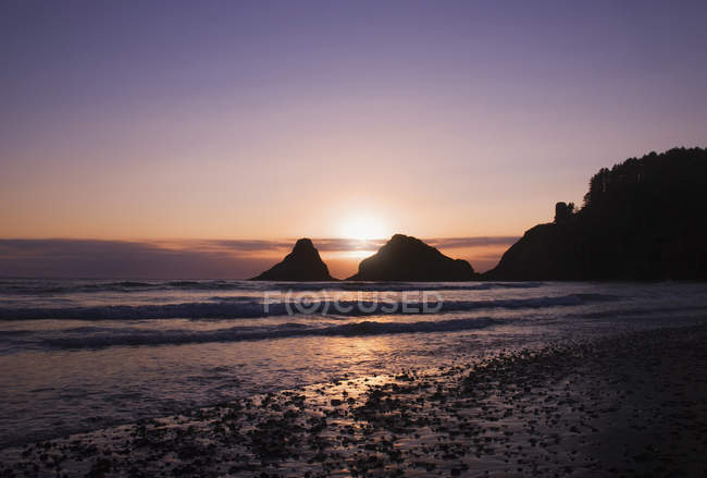 Coucher de soleil derrière les roches offshore — Photo de stock