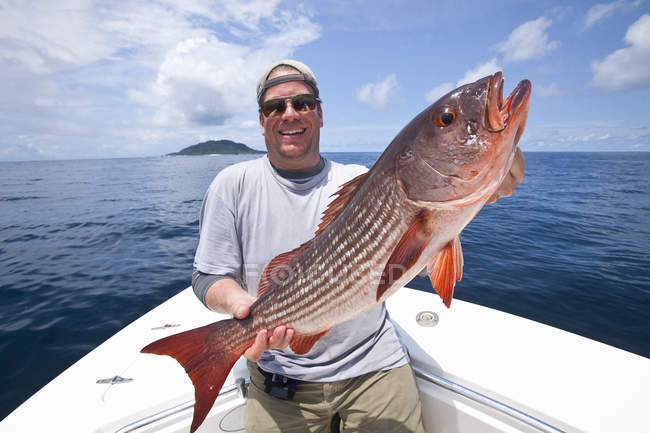 Man holding fresh caught mullet snapper on boat — Stock Photo