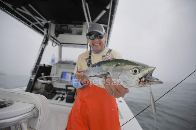 Homme tenant un faux thon germon sur un bateau — Photo de stock
