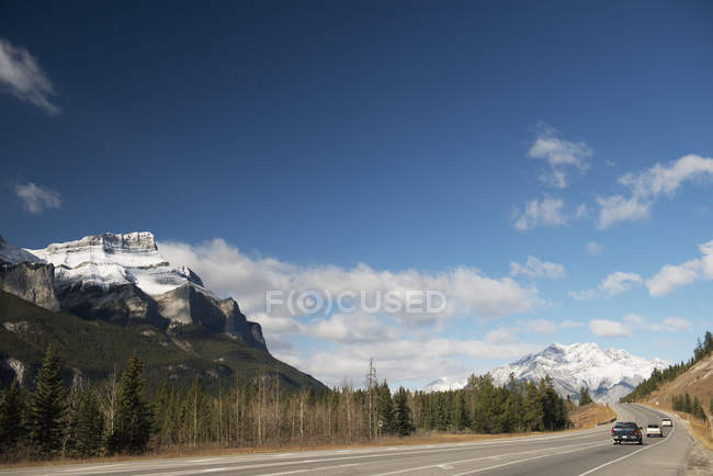 Vehículos en carretera con montañas rocosas canadienses - foto de stock
