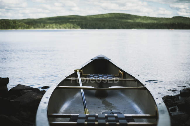 Canoë en fibre de verre au bord du lac avec montagne — Photo de stock