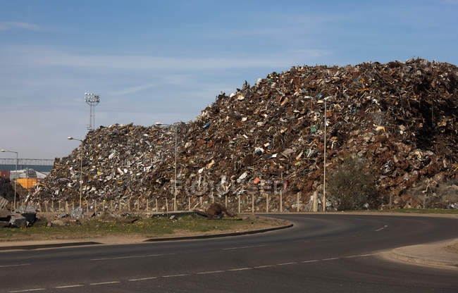 Junk yard with stack of metal trash beside road — Stock Photo