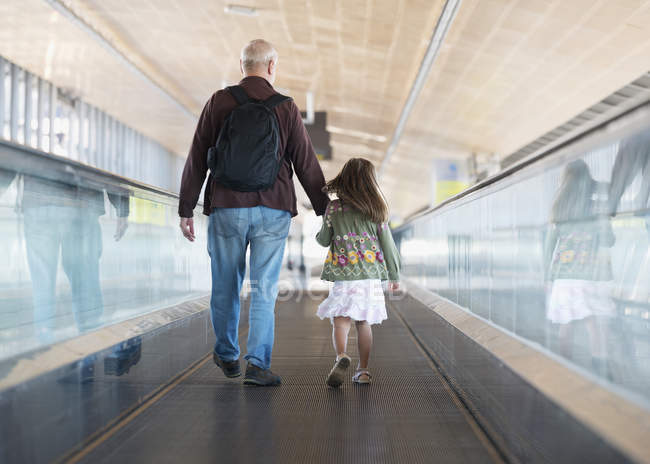 Vater und Tochter gehen auf einem fahrenden Radweg im Flughafen von Malaga; Malaga Andalusien Spanien — Stockfoto