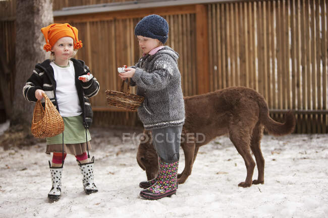 Dos chicas jóvenes comiendo sus dulces de Pascua mientras juegan en el patio, Anchorage, Southcentral Alaska, primavera - foto de stock