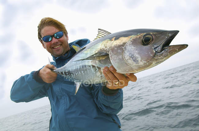Человек держит свежепойманного голубого тунца — стоковое фото