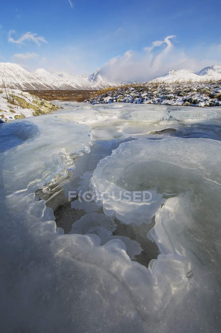 Лед в ручье, ведущий в заснеженную долину — стоковое фото