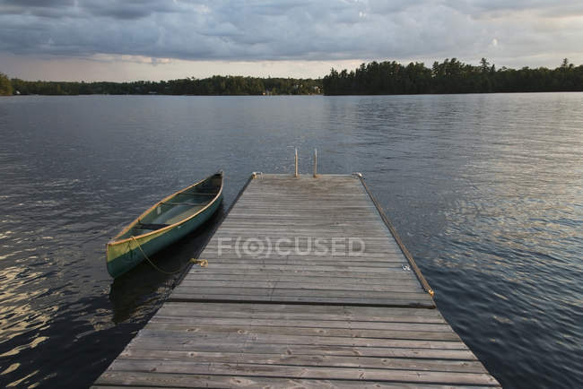 Uma canoa amarrada a uma doca de madeira — Fotografia de Stock