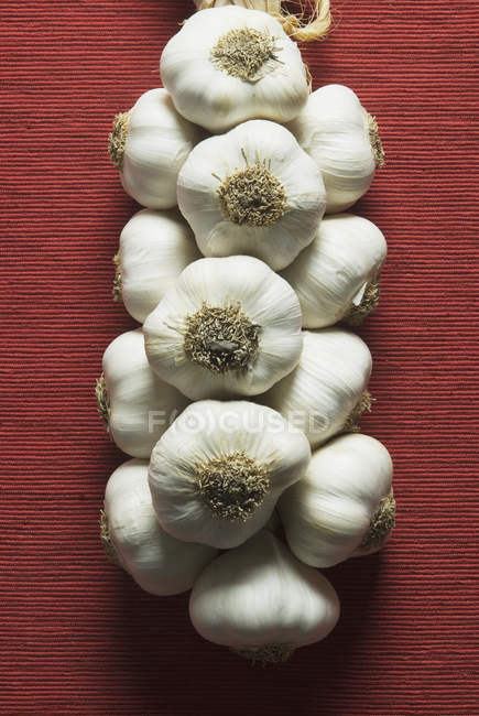 Fresh garlic heap hanging on rope — Stock Photo