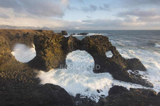 Las olas se estrellan a través del arco natural - foto de stock