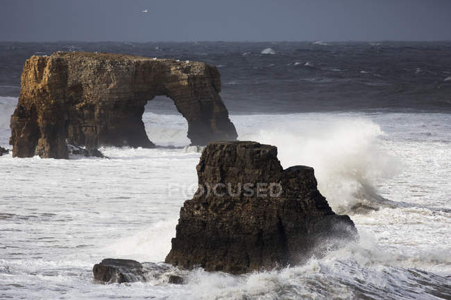 Rock formations and a natural arch in the ocean — Stock Photo