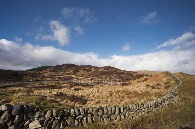 Mur de pierre traversant le paysage — Photo de stock