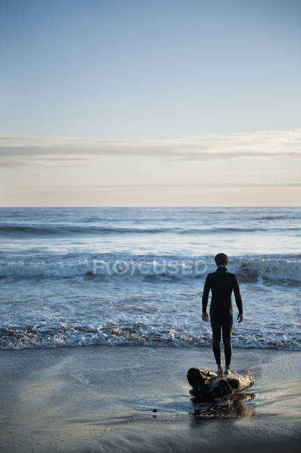 Silhouette einer Person, die an einem Strand mit Blick auf den Ozean steht — Stockfoto