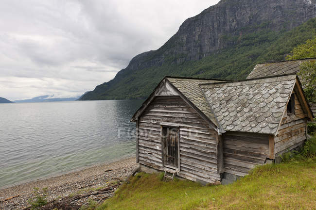 Casa di legno intemperie lungo il bordo dell'acqua — Foto stock