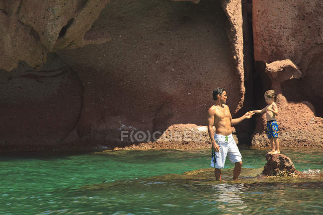 Vater und Sohn stehen auf Felsen im Ozean — Stockfoto