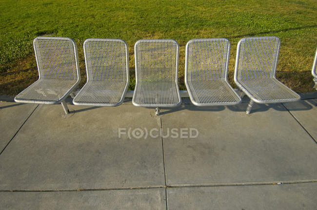 Eine Reihe silberner Stühle auf dem Zement und Gras; San Francisco, Kalifornien, Vereinigte Staaten von Amerika — Stockfoto