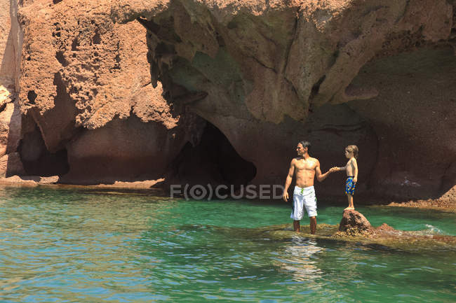 Батько і син стоїть на скелі в океані — стокове фото