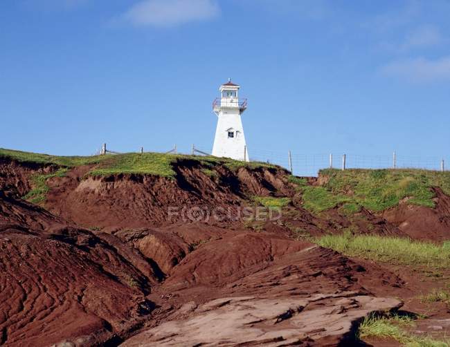 Lighthouse on hillside with blue sky — Stock Photo
