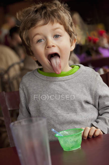 Toddler finished ice cream in restaurant and showing tongue — Stock Photo