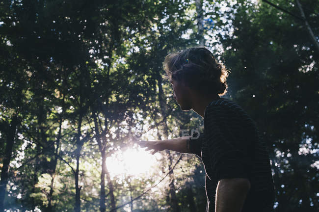 Giovane uomo che raggiunge la luce del sole in una foresta, Little River State Park; Waterbury, Vermont, Stati Uniti d'America — Foto stock